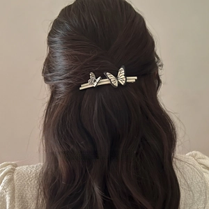 Detail view of double butterfly hair clip with black outlines on elegant silver metal bar