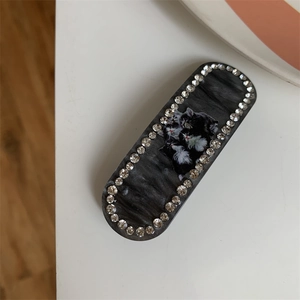 Detailed view of cat print marble hair clip with sparkling rhinestones set on white