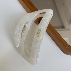 Close-up of pearl white acetate hair claw with golden Barrette la France logo