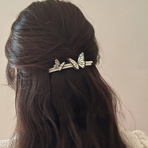 Detailed back view of vintage butterfly hair clip with black and white wings in wavy hair