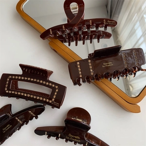 Close-up of brown resin hair claws with gold rhinestones and Barrette La France text