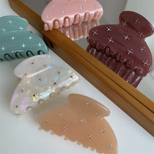Gros plan de pinces à cheveux en résine colorée avec strass sur une surface miroir