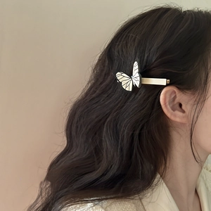 Detail of a vintage butterfly hair clip with black and white wings on a golden metal base