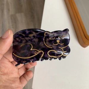Macro shot of a cat-shaped acetate hair claw featuring purple leopard print and gold outlines