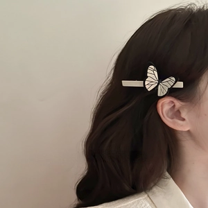 Detail view of a vintage butterfly hair clip with pearl luster on soft wavy hair