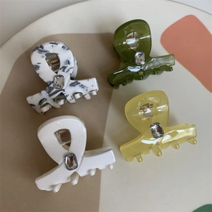 Elegant set of 4 marble texture hair claws with crystal accents on a ceramic tray