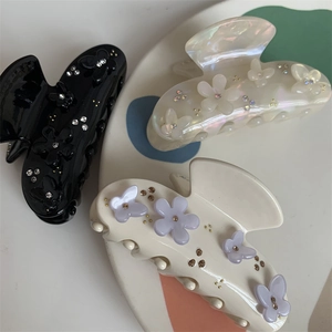 Dettaglio di fermagli per capelli neri, bianco perla e crema con fiori e strass
