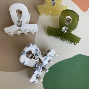 Detail of four small acetate hair claws with marble texture and crystal embellishments