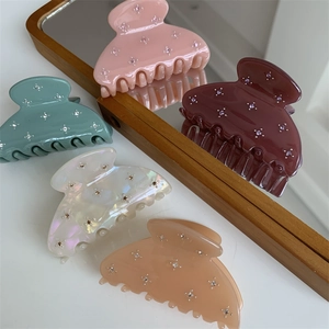 Détail de pinces à cheveux colorées en résine ornées de petits strass sur fond blanc