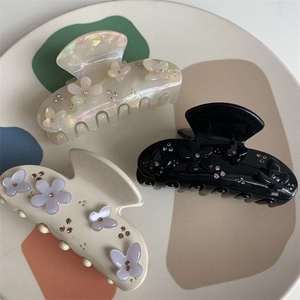 Dettaglio di tre mollette per capelli decorative con fiori e strass su un vassoio d'arte