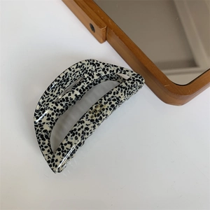 Detail view of large acetate hair claw clip with black spots and gold lettering
