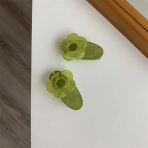Macro shot of two green floral hair clips with marble texture on a white surface