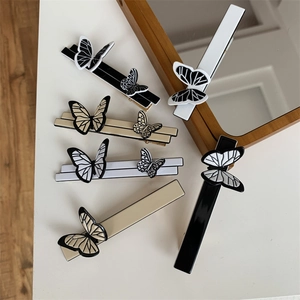 Detail of elegant butterfly hair clips in black, white and beige colors on desk