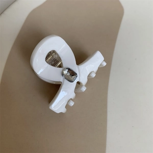 Detail of white acrylic hair claw clip featuring a rectangular clear rhinestone inlay