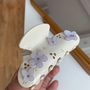 Dettaglio di un fermaglio per capelli crema con farfalle viola e strass luccicanti