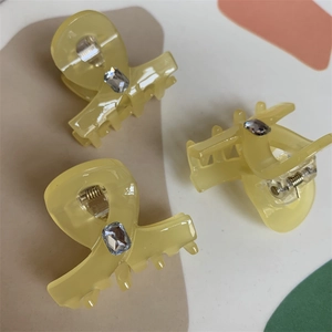 Close-up of three translucent yellow hair claws with embedded rectangular crystal stones