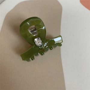 Detailed view of dark green resin hair claw clip with rectangle crystal rhinestone and metal spring