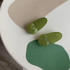 Detail view of two green heart hair clips with marble texture and jelly resin finish