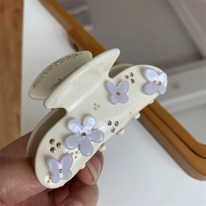 Dettaglio di un fermaglio per capelli in resina crema con fiori 3D lilla e piccoli strass