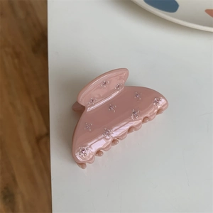 Détail de la pince à cheveux rose avec surface en résine brillante et fleurs en strass