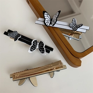 Detail of elegant black and white butterfly hair clips with golden metal alligator base