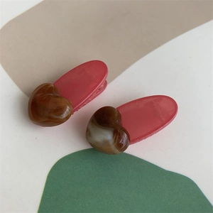 Close-up of pink jelly resin hair clips with brown amber heart charms in a set of two