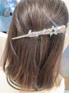 Vue détaillée de la pince à cheveux argentée avec fleur en zircon et gemme verte