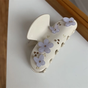 Dettaglio del fermaglio beige con farfalla e fiori viola decorato con strass lucenti