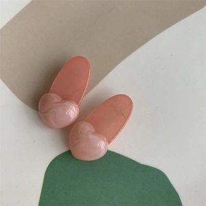 Close-up of pink heart hair clips with marble texture and translucent acetate finish