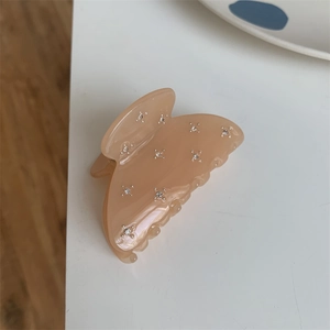 Détail macro d'une pince à cheveux en résine beige avec strass brillants et dents lisses