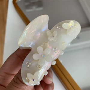 Dettaglio della pinza per capelli perlata con fiori di cristallo e farfalle