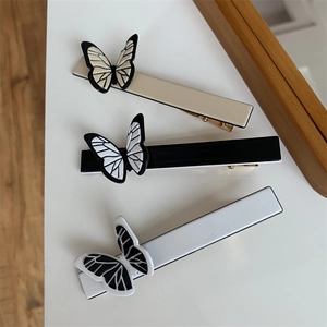 Detailed view of elegant butterfly hair clips in beige, black, and white on a surface