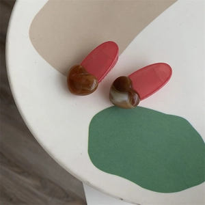 Close-up of pink hair clips with brown marble texture heart charms on a decorative tray