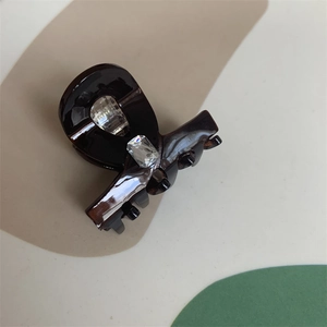Detail of a dark tortoise resin hair claw clip with a luxury rectangular gemstone inlay
