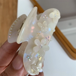 Dettaglio della molletta per capelli perlata con fiori, farfalle e strass colorati