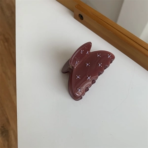 Détail d'une pince à cheveux papillon avec strass violets sur base couleur prune