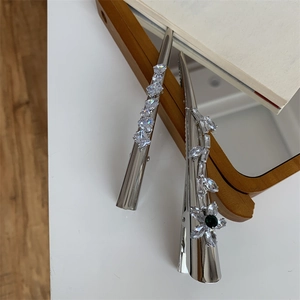Détail des barrettes à cheveux argentées avec zircons blancs et motifs de fleurs vertes