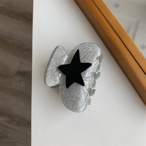 Detailed top view of grey star hair claw clip with silver sequins and black star motif