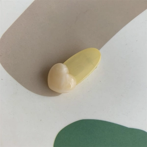 Close-up of heart and oval acrylic jelly hair clips in soft yellow and cream colors