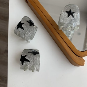 Detail of grey star hair claw clips with silver glitter and black star patterns
