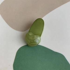 Detail of olive green hair clip featuring a marble-textured light green heart element