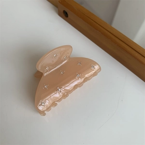 Détail d'une pince à cheveux en résine pêche ornée de strass brillants et élégants