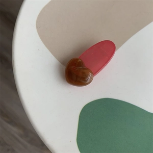 Detailed macro view of heart-shaped marble resin hair clip with red jelly base