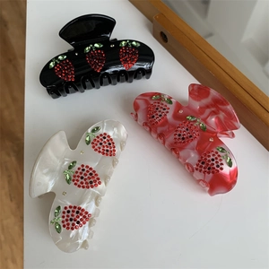 Dettagli delle pinze per capelli con fragole di strass in nero, bianco e rosso marmo