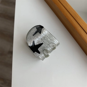 Detail of grey star hair claw clip with metallic finish and black star patterns