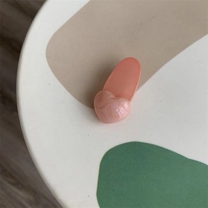 Detail view of pink heart hair clip with marble texture on minimalist background