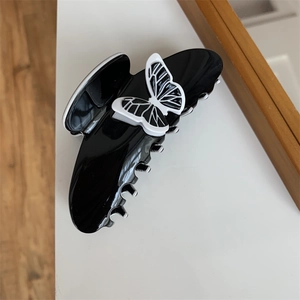 Detail of a black glossy hair claw clip featuring a 3D butterfly with fine textures