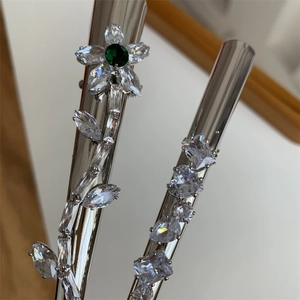Détail des barrettes argentées avec fleurs d'émeraude et pierres de zircon géométriques