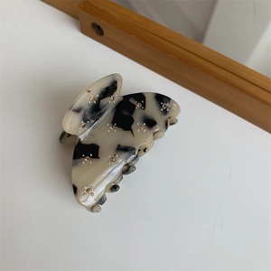 Détail de la pince papillon avec motif marbré noir et blanc et strass brillants