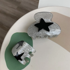 Detail view of two silver star hair clips with black star accents and metallic finish